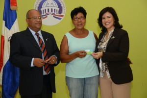 Margarita Cedeño junto al director de la ADESS, Ramón González, entrega una tarjeta a una beneficiaria.