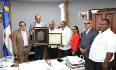 El director de Pro Consumidor, Eddy Alcántara, momento en que recibe las placas de reconocimiento por parte de los comerciantes.